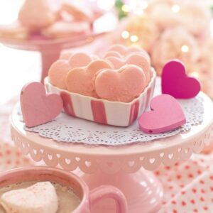 Indulge in heart-shaped pink macarons on a romantic Valentine's Day setting.